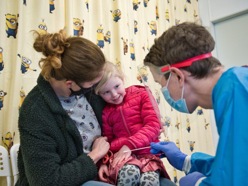 Medewerker bereid klein kind bij moeder op schoot voor op test